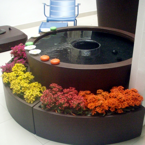 Fuente de fibra de vidrio modelo Uruguaya con flores de temporada a su alrededor